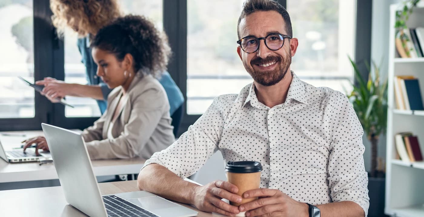 Asesor de Circle Club sonriendo con un café en la oficina